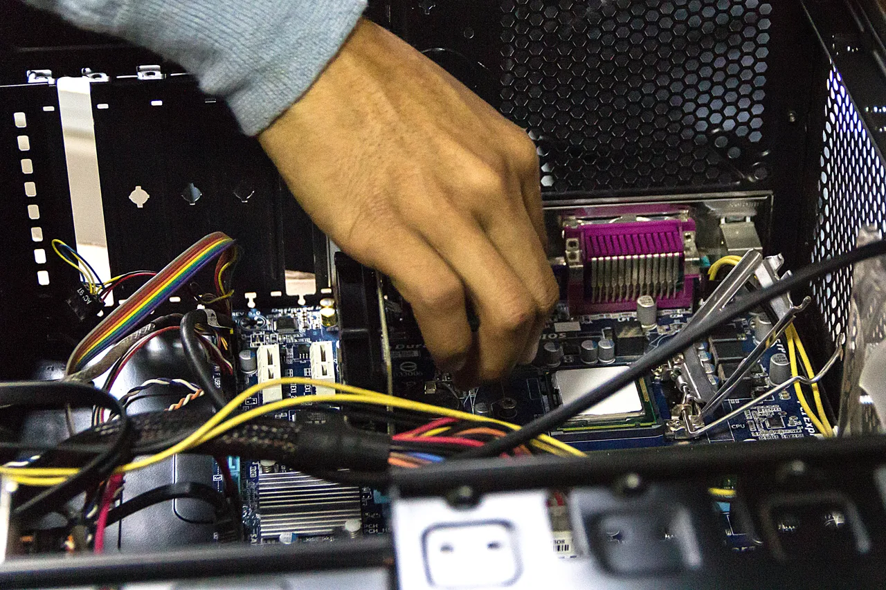 Gros plan sur les mains d'un technicien effectuant une opération de maintenance à l'intérieur d'un boîtier d'ordinateur, au niveau du processeur